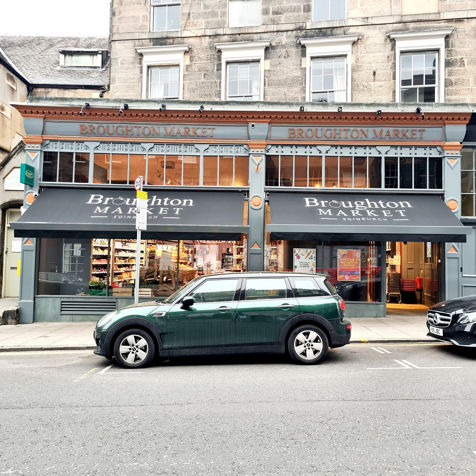The Broughton Market shopfront today — dark-green fascia lettered Broughton Market on a New Town stone tenement, a green Mini parked outside