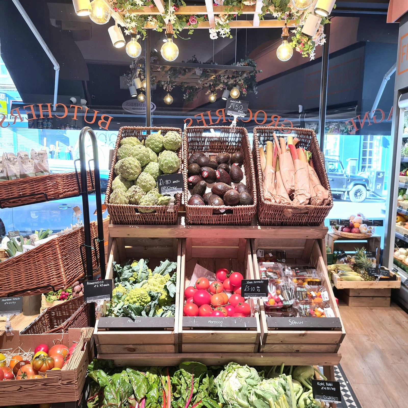 Inside the shop — baskets of fresh produce and vegetables beneath a hanging Butcher sign