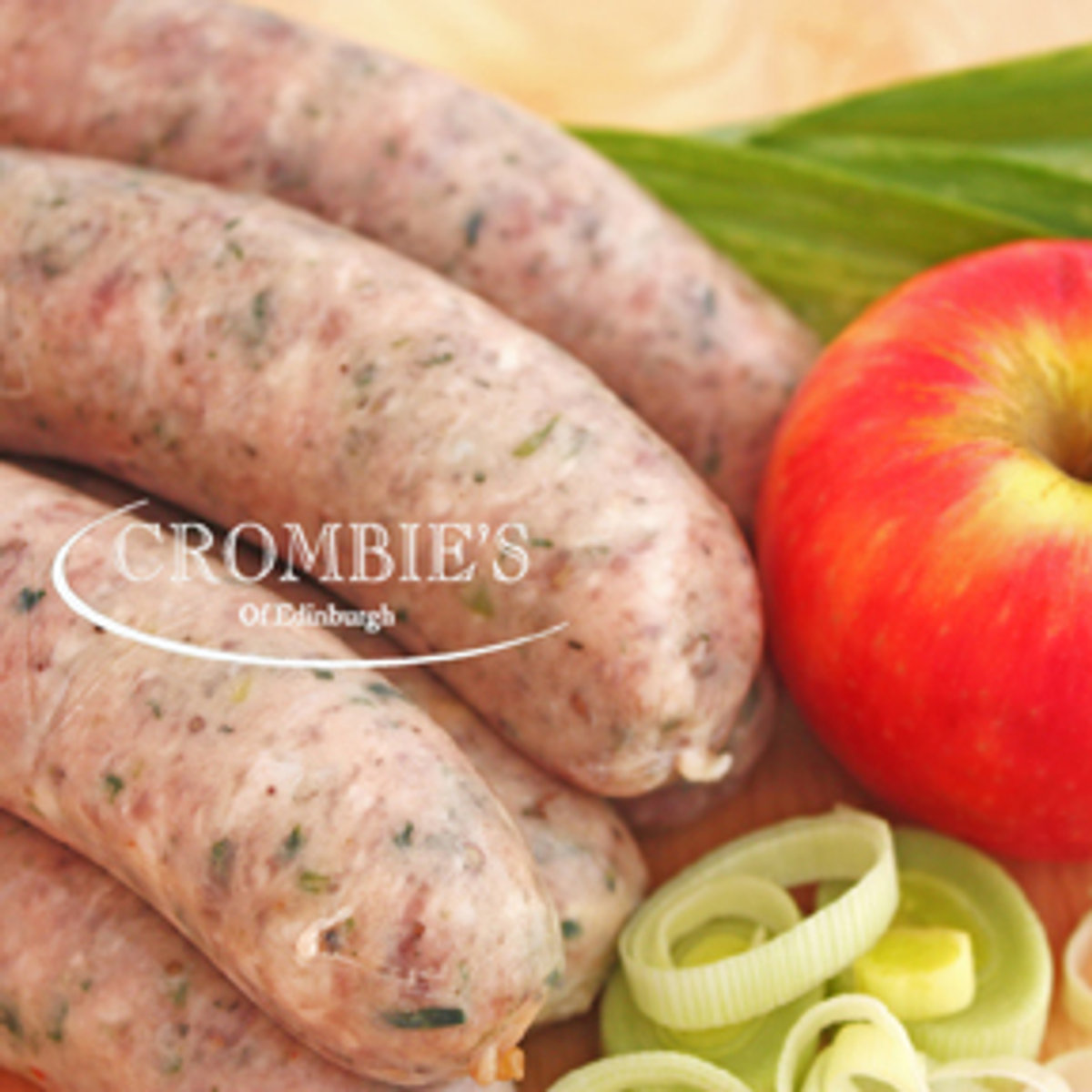 Herby pork sausages beside a fresh apple