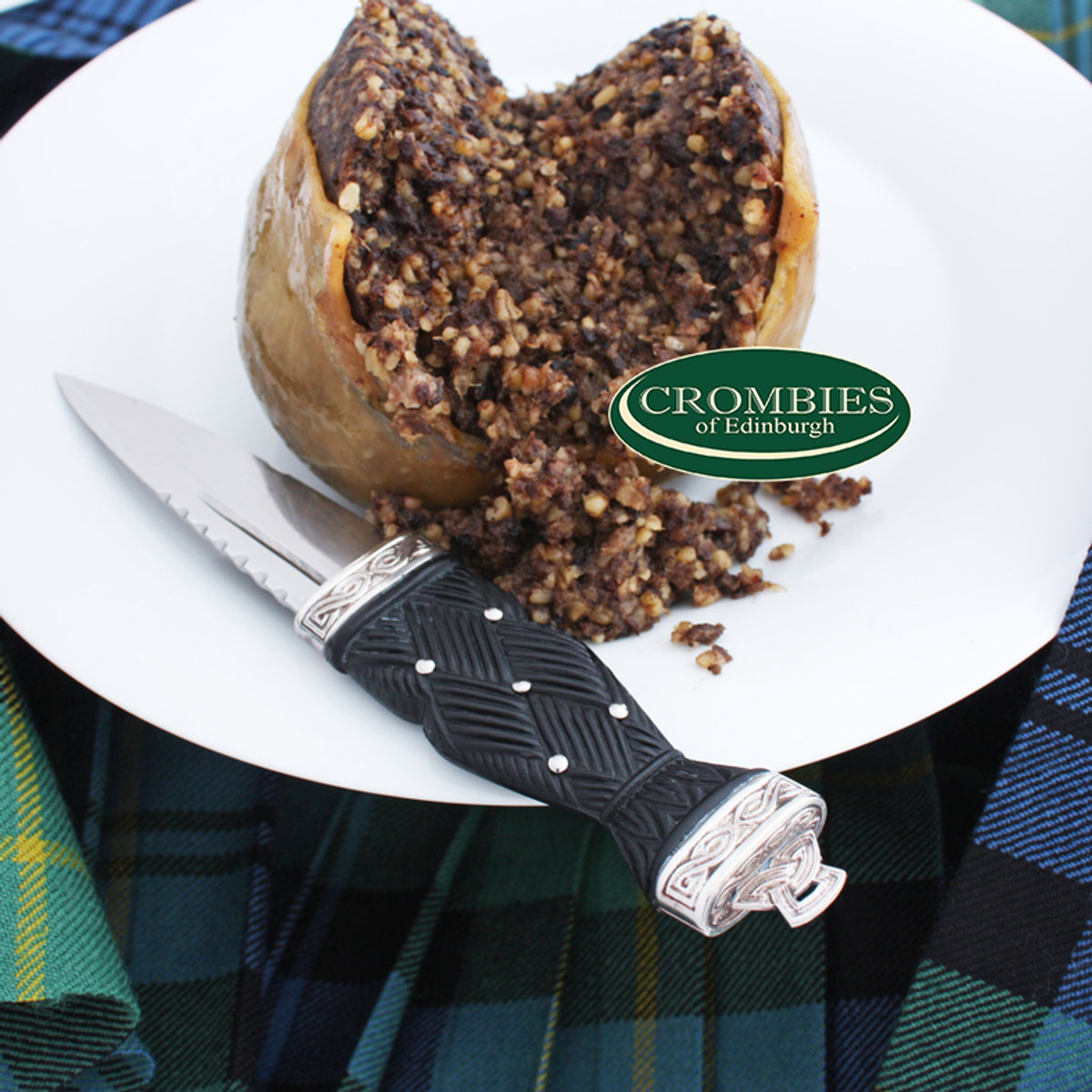 Traditional Scottish haggis on a plate, cut open, with a sgian-dubh knife on tartan