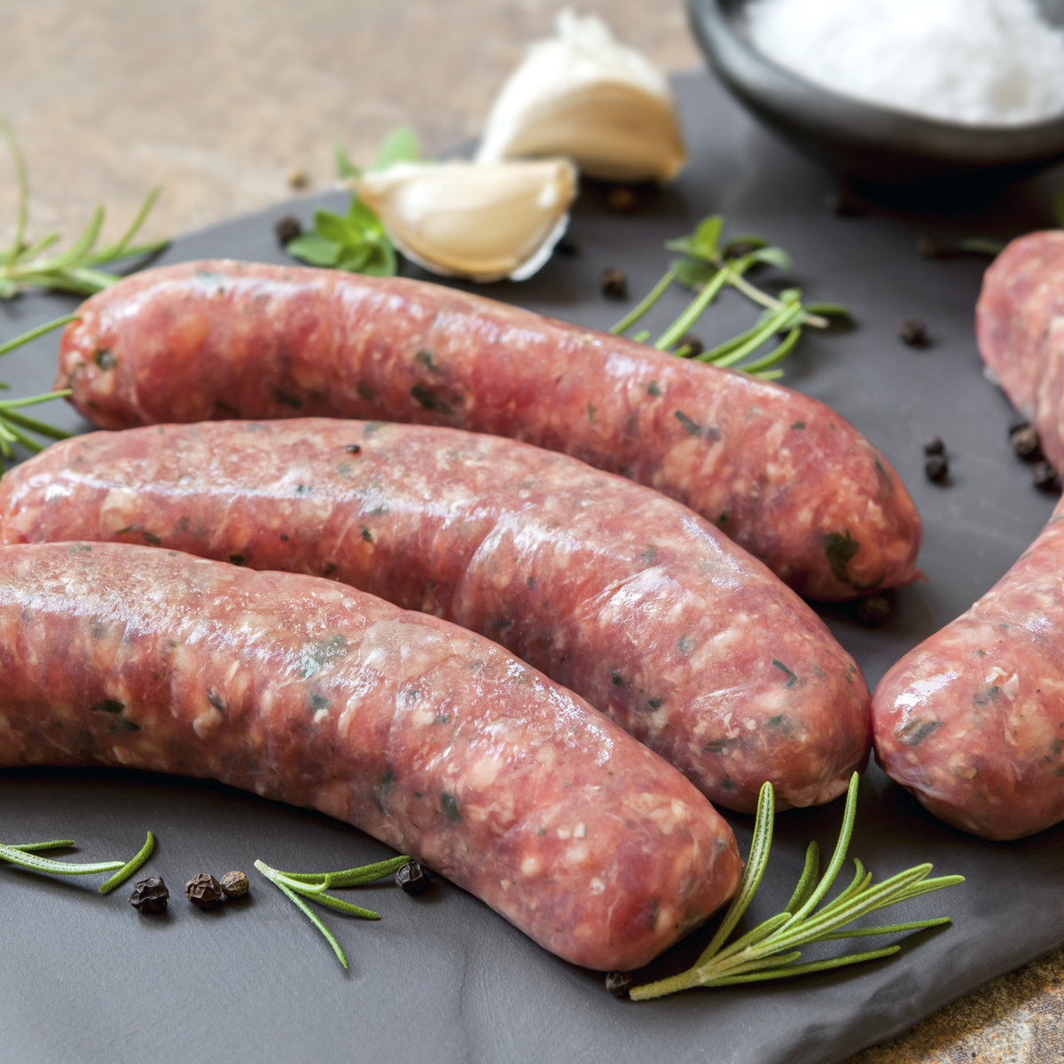Fresh sausages on slate with garlic and herbs